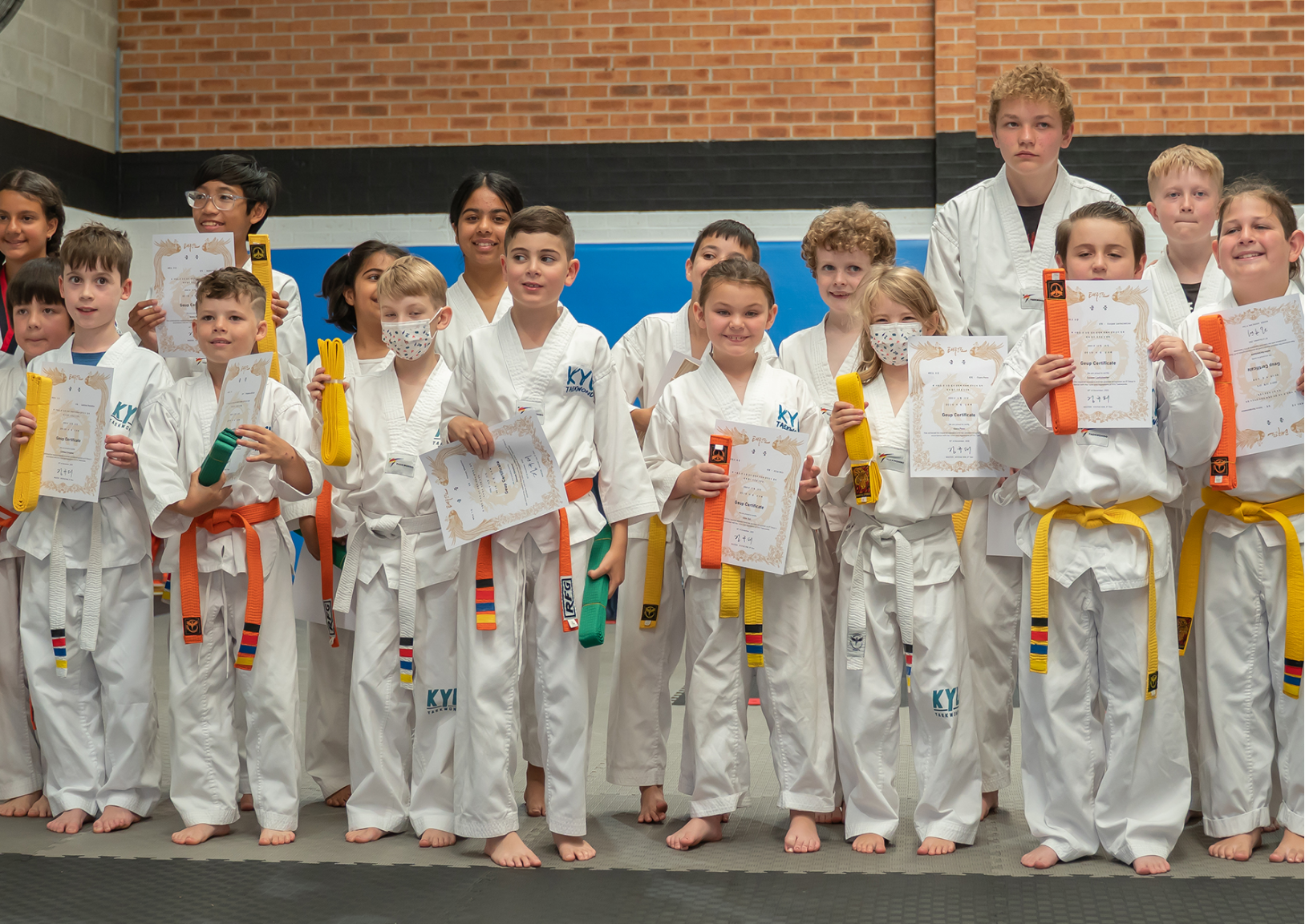 Students of all ages showing their belt achievements in traditional dojo setting